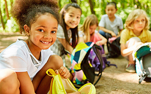 young children reach into backpacks while on a field trips