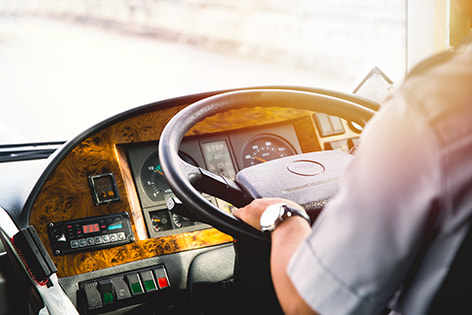 a bus driver sits at the wheel of charter bus